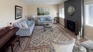 A living room with a fireplace, a sofa, a coffee table, and a patterned rug. - 3BR Edgemont Retreat | Views, Deck, Near Grouse (North Vancouver)