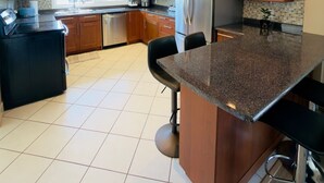 A modern kitchen with wooden cabinets, stainless steel appliances, and a granite island. - 3BR Edgemont Retreat | Views, Deck, Near Grouse (North Vancouver)