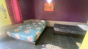 A room with two beds, one with a floral bedspread and the other with a geometric pattern.