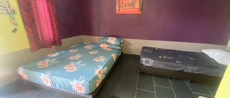 A room with two beds, one with a floral bedspread and the other with a geometric pattern.