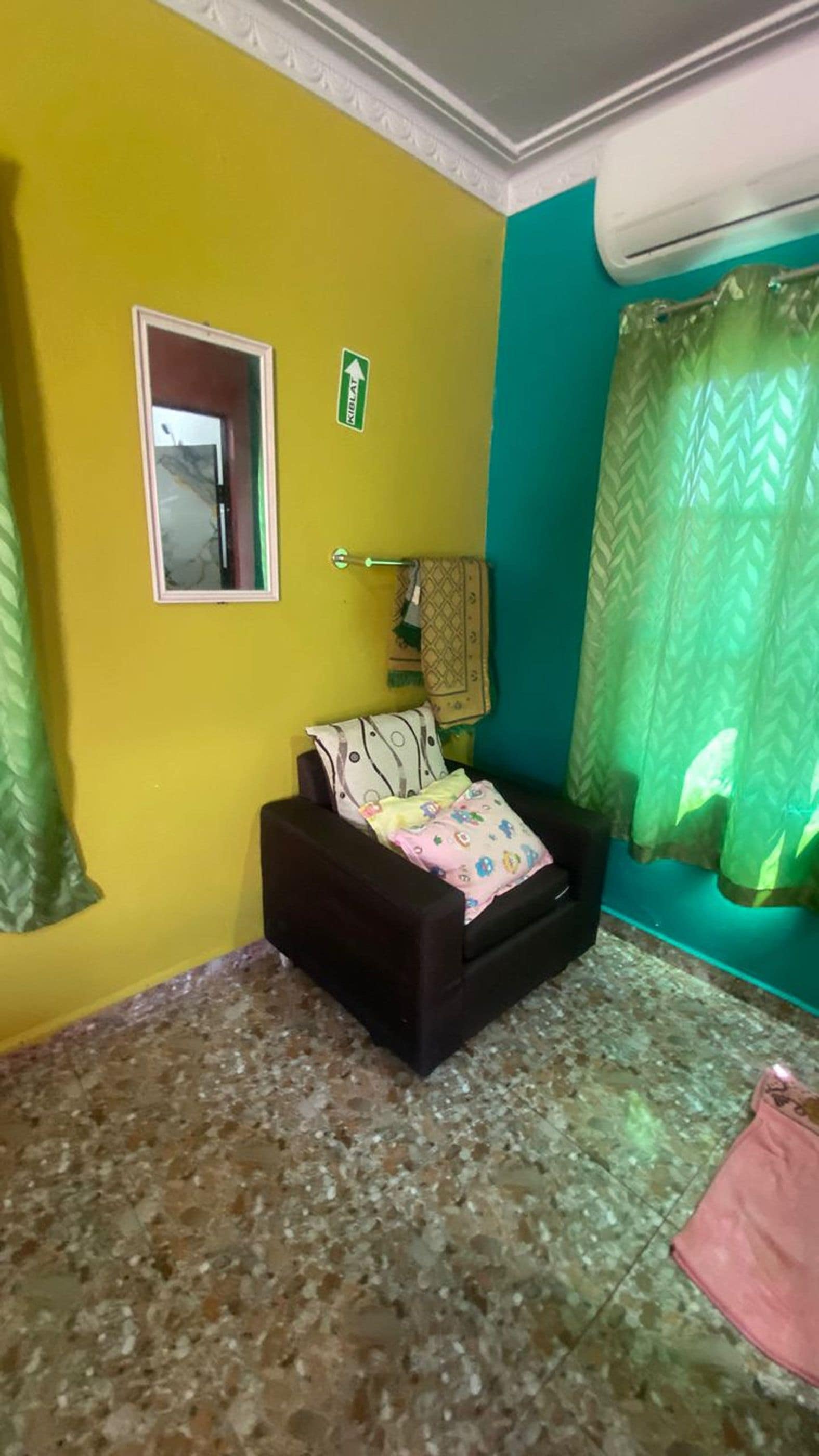 A room with a bed, a window with curtains, a door with a mirror, and a wall with a door handle.