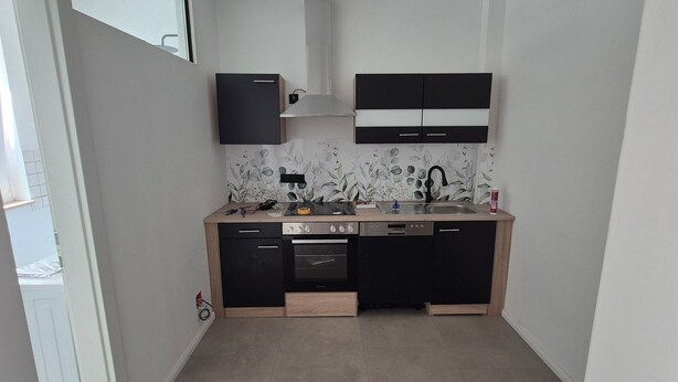 A compact kitchen with black cabinets, a built-in oven, and a sink. - Quiet vacation apartment near Lake Klopeinersee (Völkermarkt)