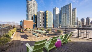 Een dakterras met buitenmeubilair en uitzicht op hoge gebouwen.