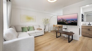 Een moderne woonkamer met een bank, een salontafel, een televisie en een eethoek.