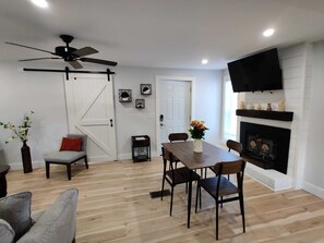 Ein Essbereich mit Holztisch und Stühlen, einem Kamin, einem Deckenventilator und einem Wand-Fernseher.