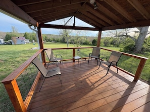 Eine Holzterrasse mit Stühlen und einem Tisch, mit Blick auf eine Rasenfläche.