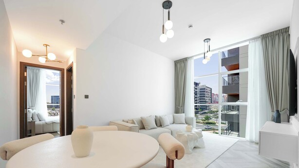 Una sala de estar moderna con una mesa redonda, sofá y ventanas amplias que ofrecen vistas a la ciudad.