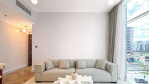 Una sala moderna con un sofá seccional, una original mesa de centro blanca y un ventanal con vistas a la ciudad.