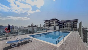 Una piscina en la azotea con vistas despejadas al horizonte de la ciudad, un flotador salvavidas y una tumbona.