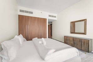 A hotel room with a bed, a wardrobe, a mirror, and a radiator. - Luxury 1-Bed with Burj Khalifa Views in Downtown (Dubai)