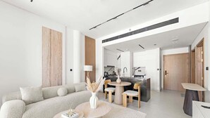 Una sala moderna con sofá, mesa de centro y una cocina al fondo.