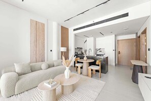 A modern living room with a sofa, coffee table, and a kitchen in the background. - Luxury Burj-View in Business Bay with pool and gym (Dubai)