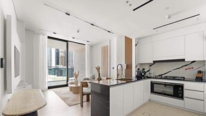 Una cocina moderna con una isla central, horno empotrado y armarios blancos.