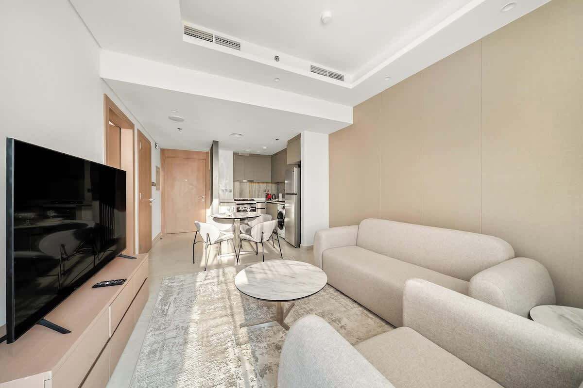 A modern living room with a flat-screen TV, a round coffee table, and a sofa.