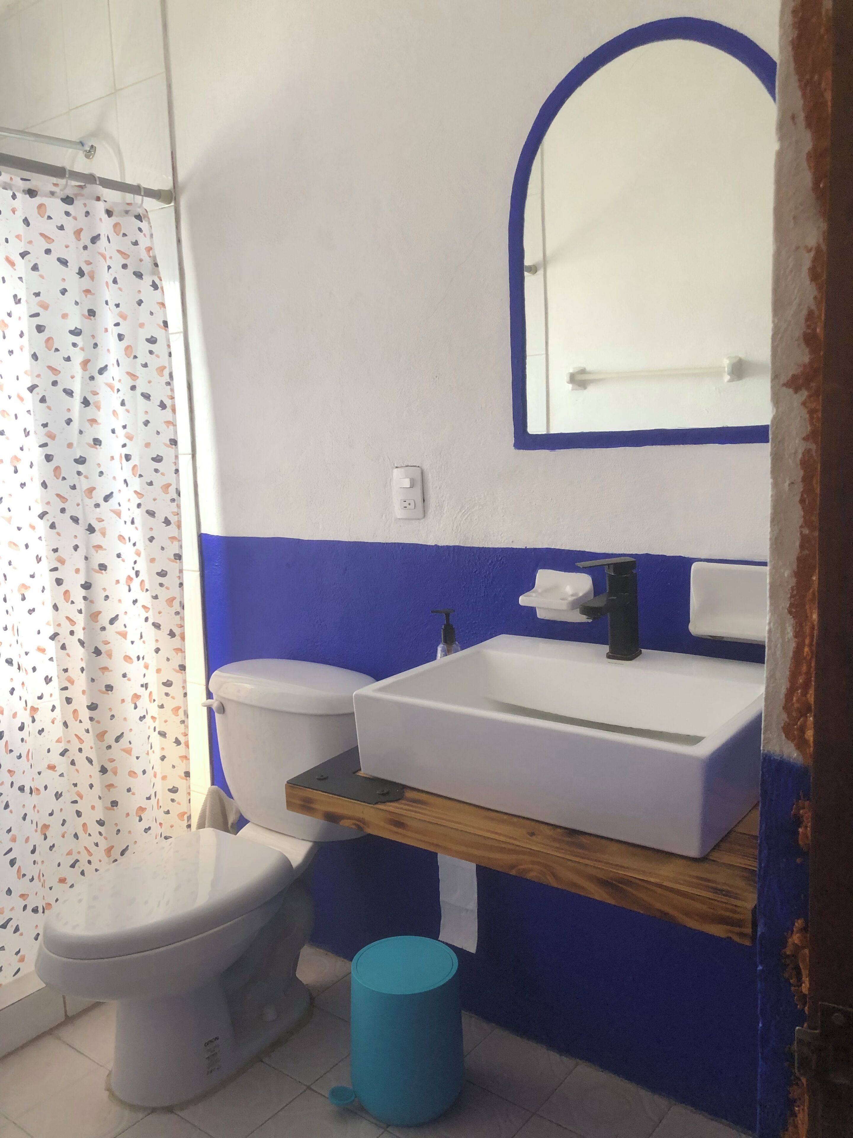 A bathroom with a toilet, sink, mirror, and shower curtain.