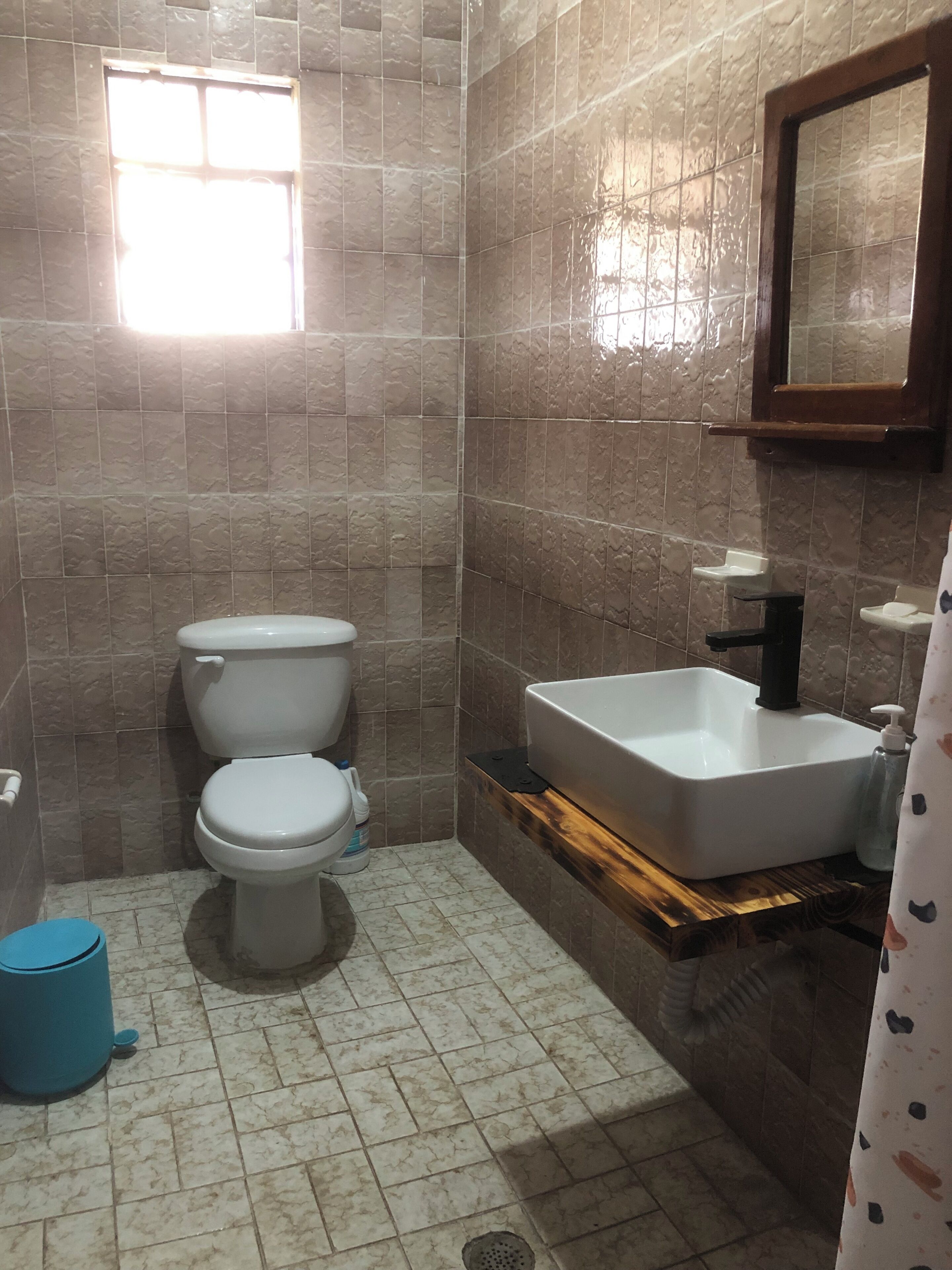 Een badkamer met toilet, wastafel en raam.
