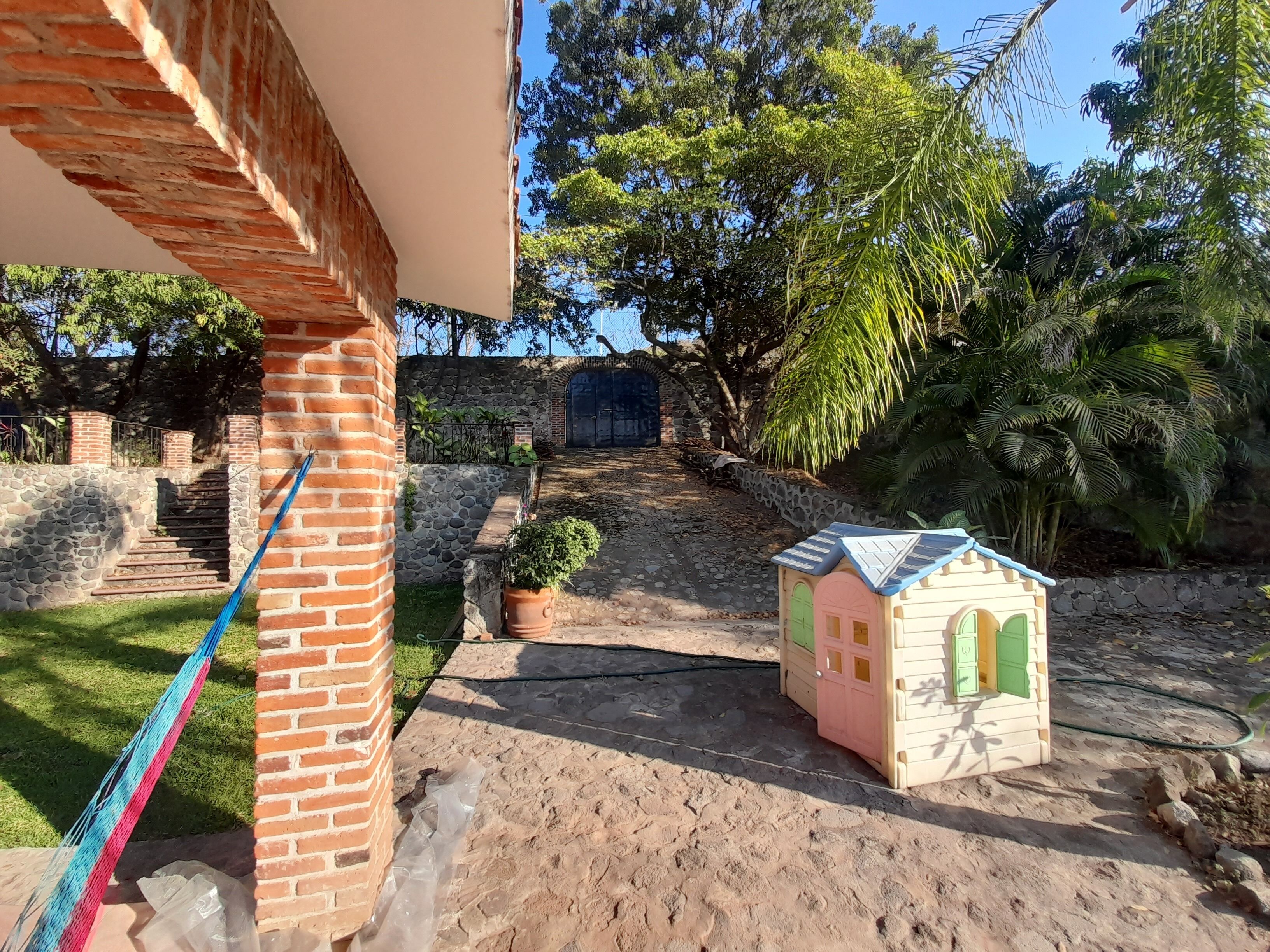 A brick building with a small garden, a playhouse, and a stone staircase leading to a gate.