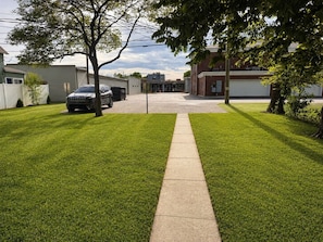 A residential driveway leading to a garage, a lawn with a sidewalk, and a tree.