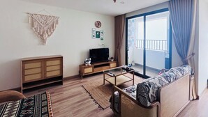 A living room with a sofa, TV, wooden cabinet, and a balcony with curtains. - ARIES HOUSE SAPA PROVINE, Apartment in the clouds (Sa Pa)
