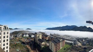 A high-rise building with multiple floors, a construction site with tents and equipment, and a mountainous landscape in the background. - ARIES HOUSE SAPA PROVINE, Apartment in the clouds (Sa Pa)