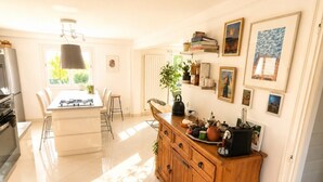A modern kitchen with a central island, wooden cabinets, and a dining area with chairs. - Maison 8p avec jardin, 2 salons & parking (Sainte-Geneviève-des-Bois)