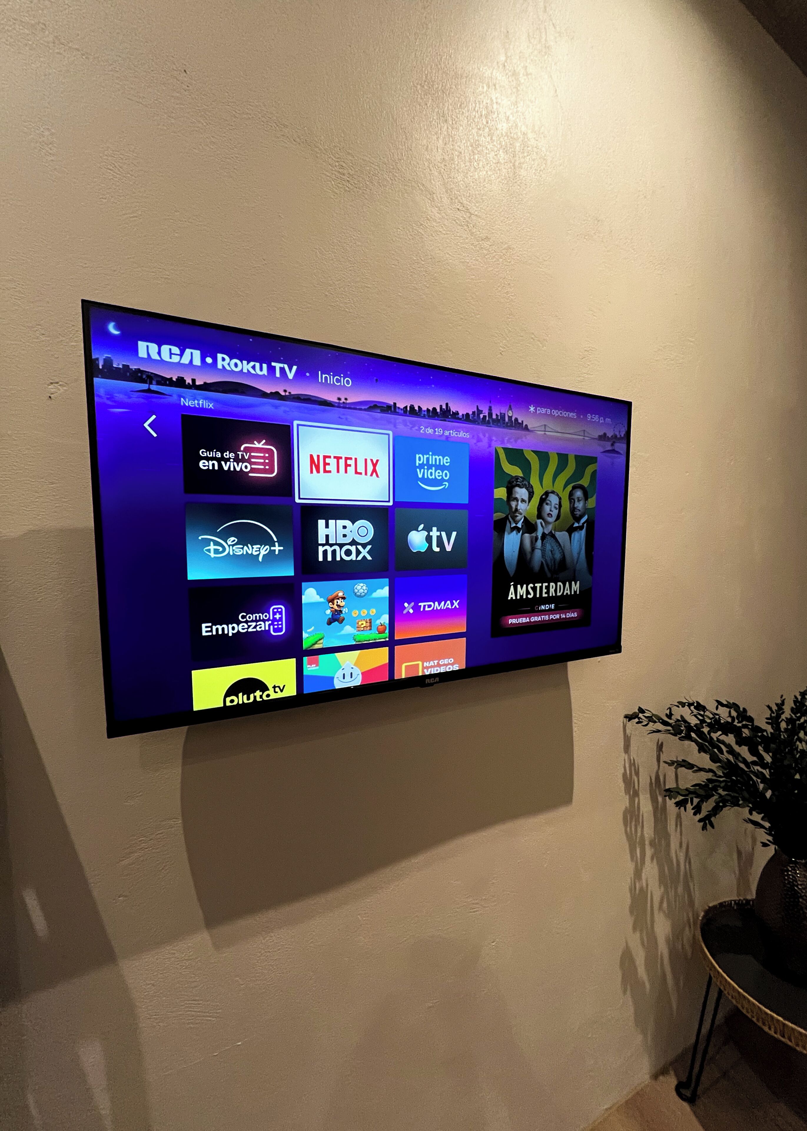 Televisor de pantalla plana montado en la pared mostrando varios logotipos de servicios de streaming.