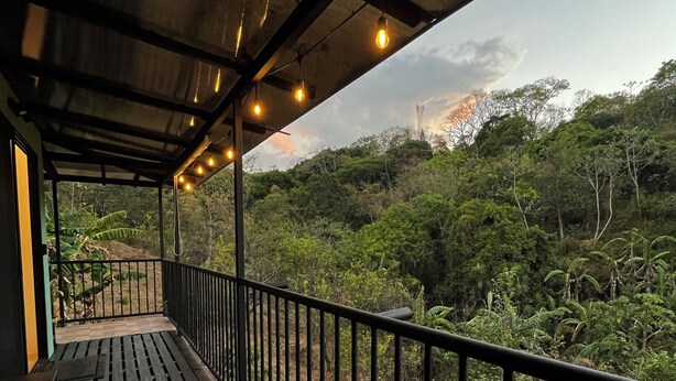 A wooden deck with a metal railing overlooking a lush, green landscape. - Tropical Forest Experience with Hot Tub, AC & Terrace (Atenas)