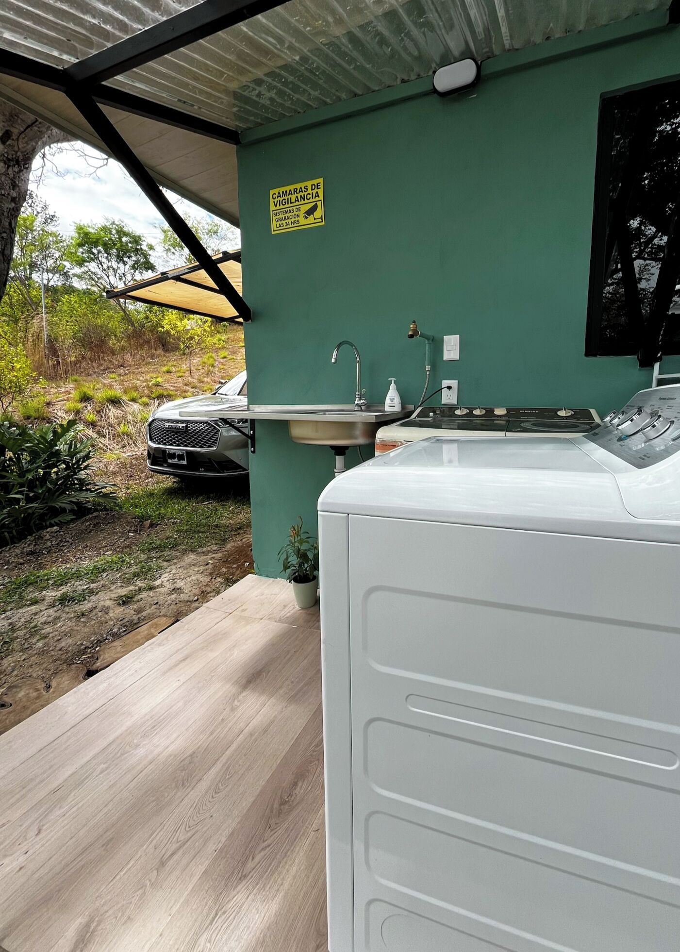A room with a sink, a water heater, and a car parked outside.