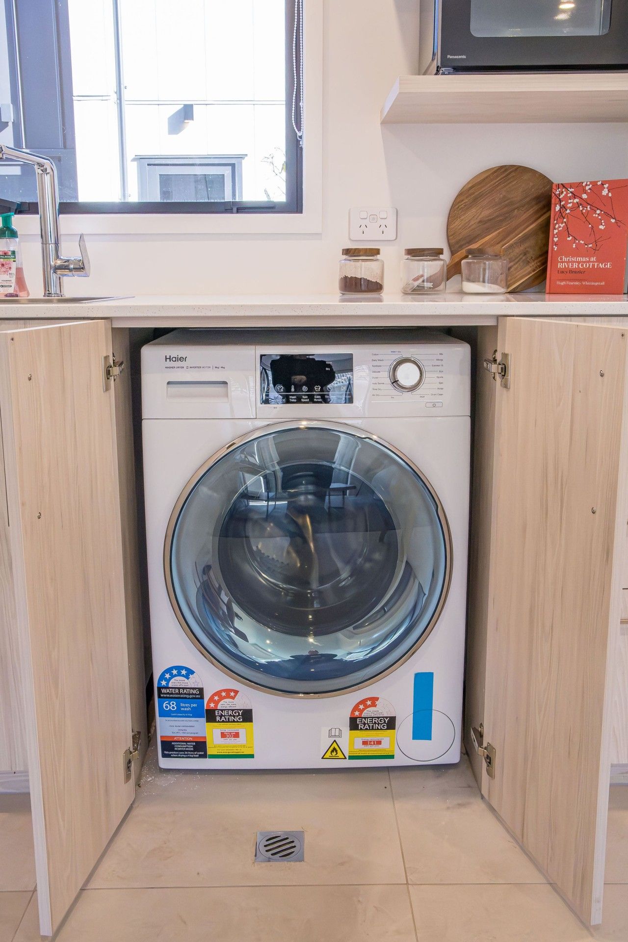 A compact washer and dryer unit installed in a kitchen cabinet.