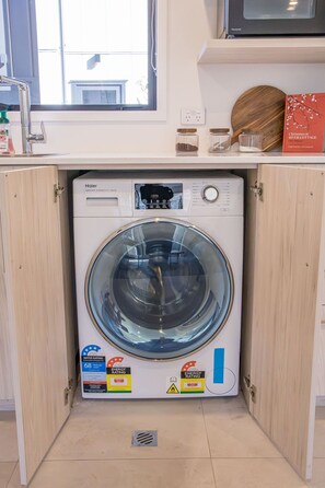 A compact washer and dryer unit installed in a kitchen cabinet. - Stylish Townhouse for Families & Groups (Lower Hutt)