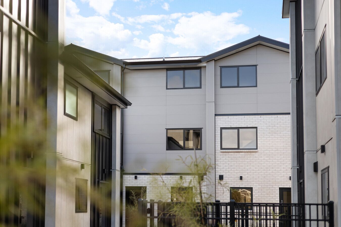 Un immeuble résidentiel moderne à plusieurs étages, doté d’un toit plat, de grandes fenêtres et d’une façade en briques.