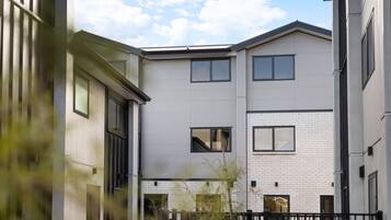 Un immeuble résidentiel moderne à plusieurs étages, doté d’un toit plat, de grandes fenêtres et d’une façade en briques.