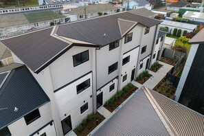 Un edifici residencial de diverses plantes amb un disseny modern, amb teulada plana, grans finestres i una petita zona de jardí.