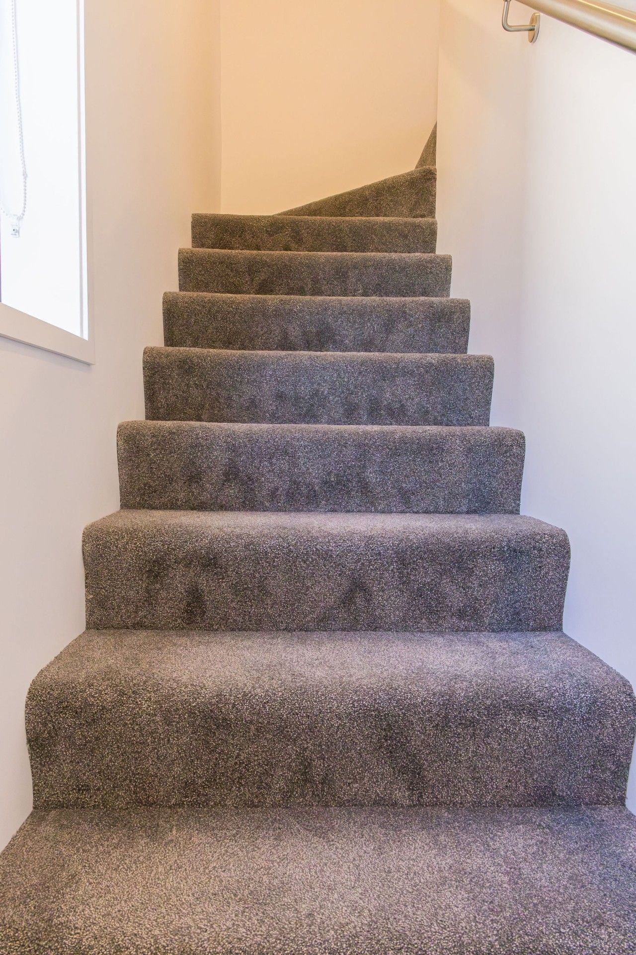 A carpeted staircase with a handrail on the right side.