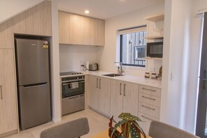 A modern kitchen with a stainless steel refrigerator, built-in oven, and microwave. - Stylish Townhouse for Families & Groups (Lower Hutt)