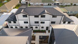 A multi-story residential building with a central courtyard, multiple balconies, and a flat roof design. - Stylish Townhouse for Families & Groups (Lower Hutt)
