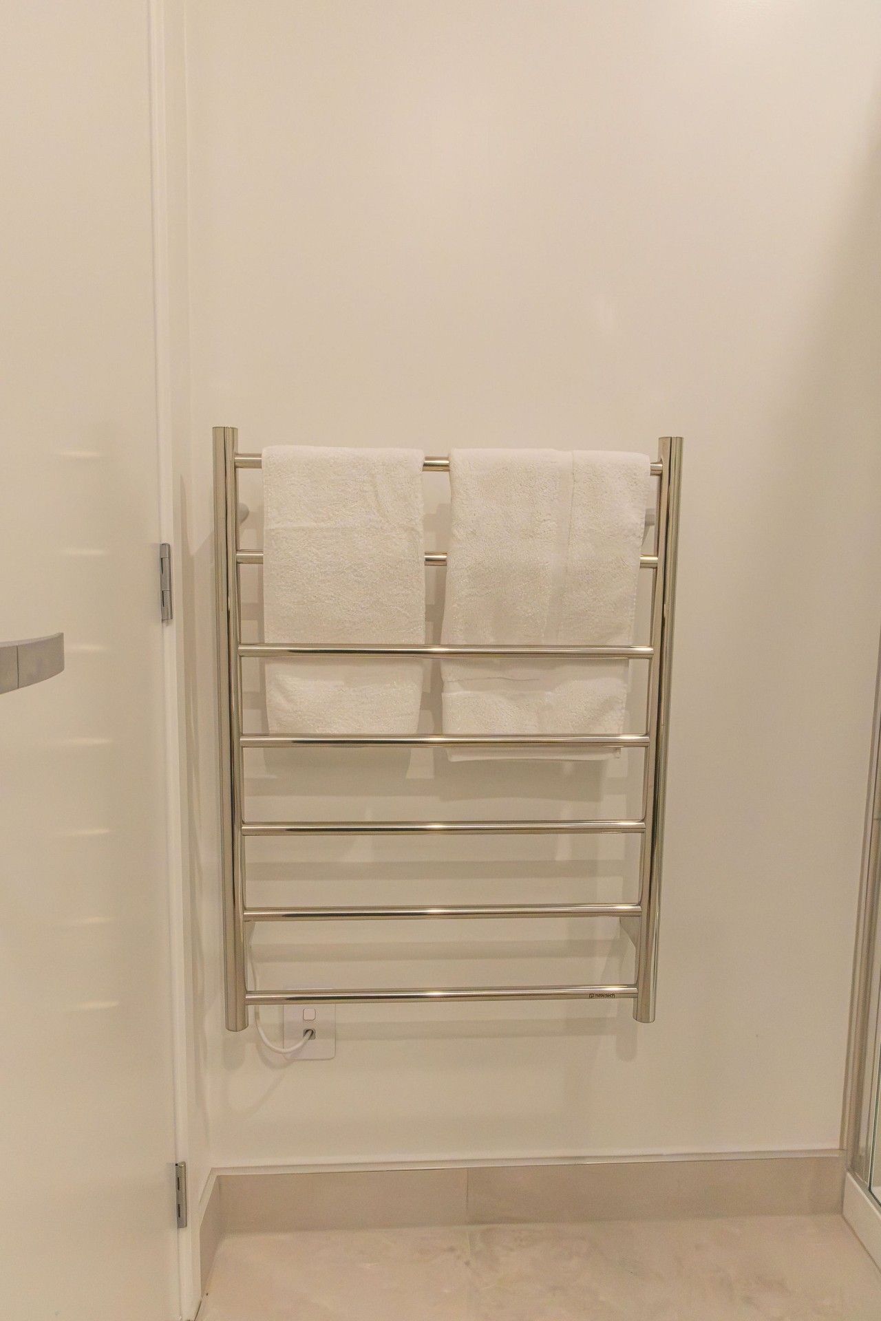 A bathroom with a towel rack holding two towels.