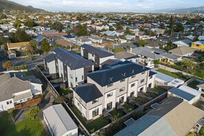Een woonwijk met moderne huizen, waaronder een groot, gelijkvloers gebouw met twee verdiepingen en veel ramen.