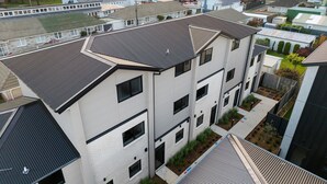 Un edifici residencial de diverses plantes amb un disseny modern, amb teulada plana, grans finestres i una petita zona de jardí.