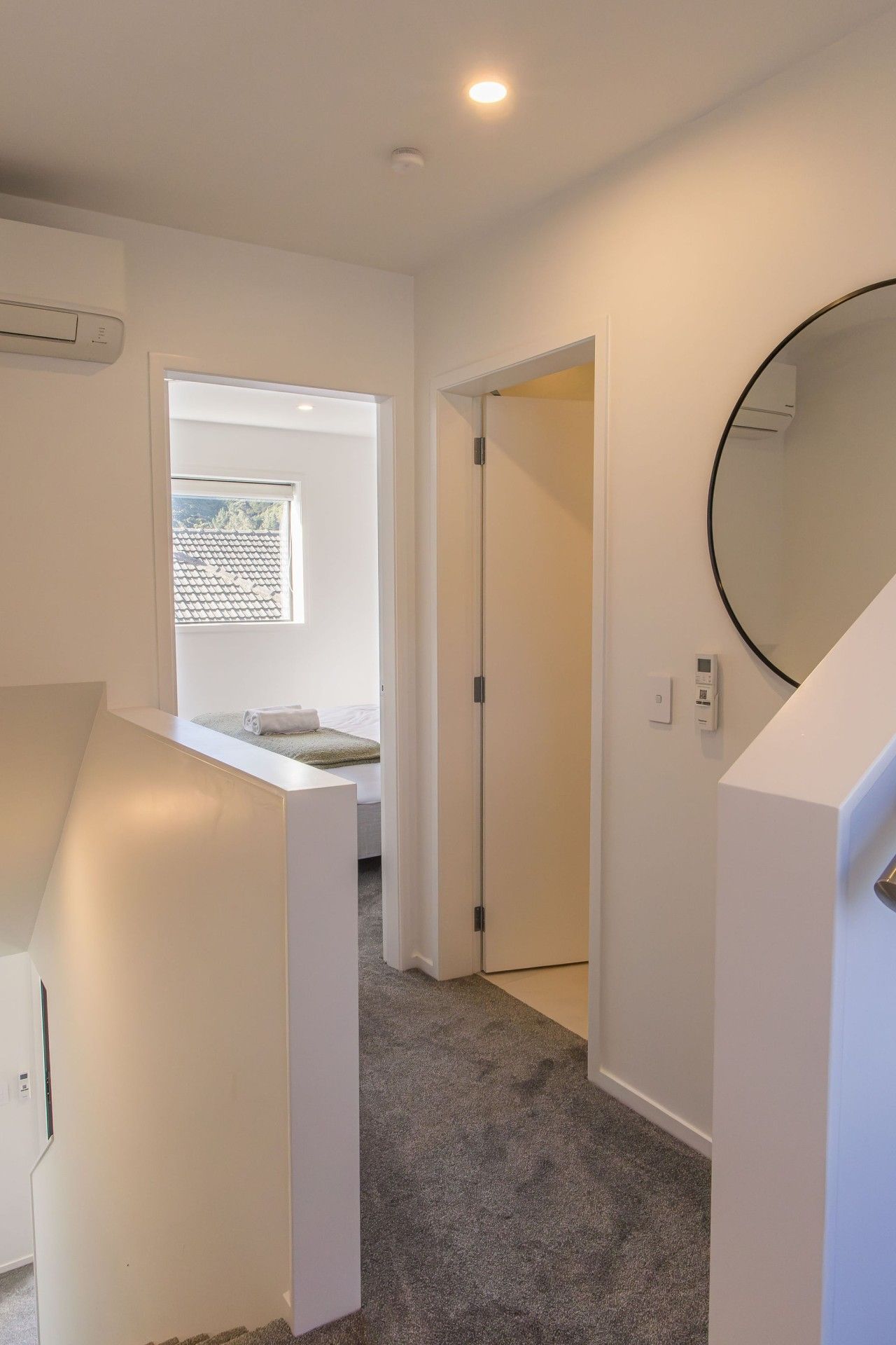 A hotel room with a bed, a window, a door, and a small balcony.