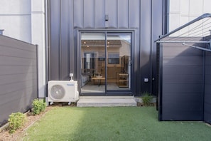 Un bâtiment moderne doté d’une entrée avec une porte vitrée coulissante, d’un espace cuisine visible et d’un appareil de climatisation.