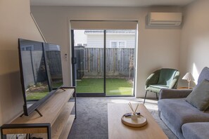 Een woonkamer met een bank, een salontafel en een tv op een dressoir.