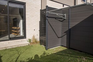 Ett modernt hus med en stor skjutdörr i glas, en mörk yttervägg och en välskött gräsmatta.
