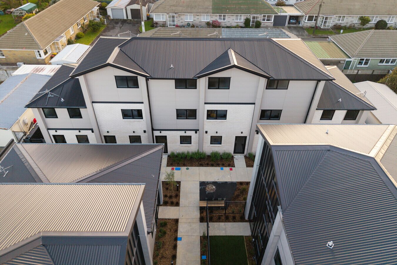 A multi-story residential building with a central courtyard, multiple balconies, and a flat roof design.