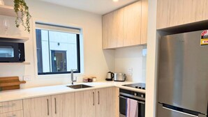 Una cocina moderna con armarios de madera clara, electrodomésticos de acero inoxidable y un ventanal que proporciona luz natural.