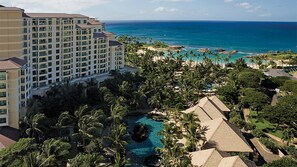 A resort with a large building, a swimming pool, and a beach view.
