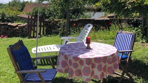 An outdoor seating area with a table and chairs, a blue umbrella, and a stone wall in the background. - ROOM for 2 adults 1 h30 from TOULOUSE - Pets under -3 kg accepted. (SAINT-PROJET)