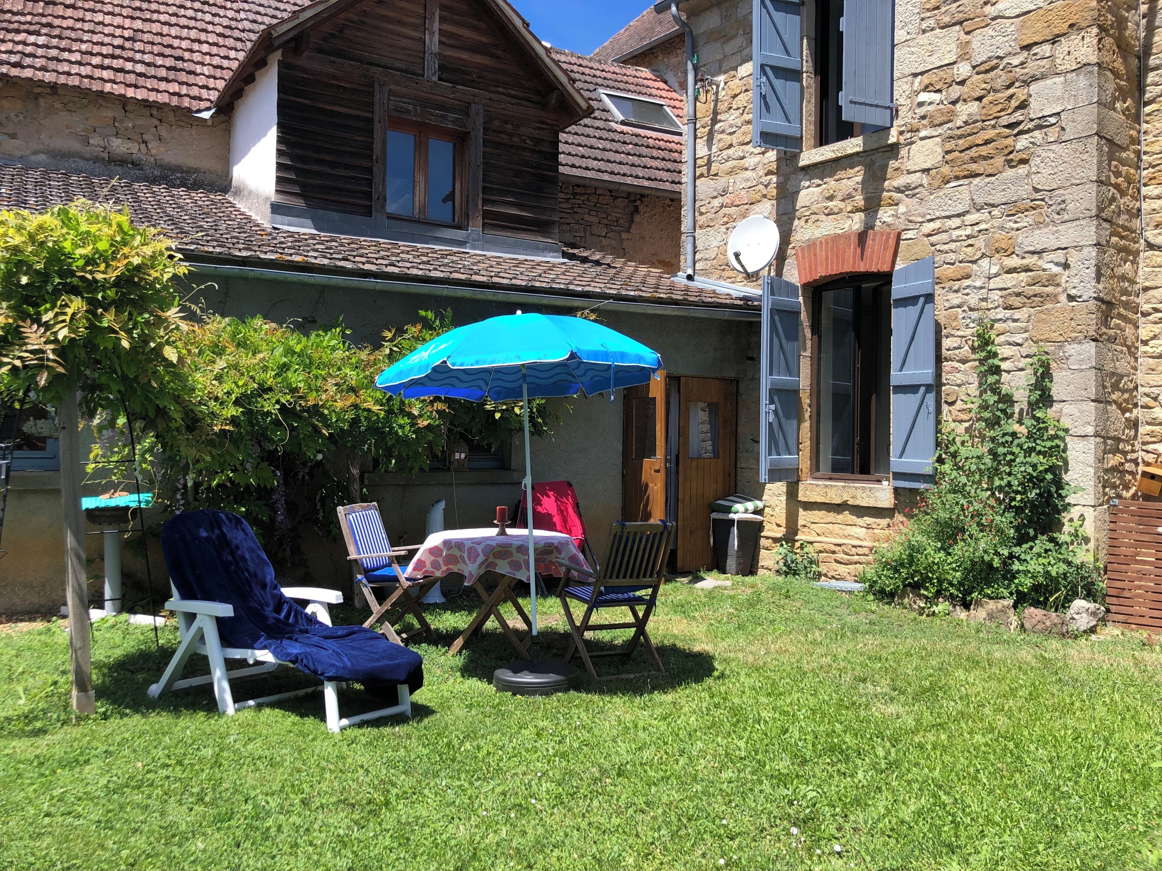Een terras met tuinmeubilair, een tafel en een blauwe parasol.