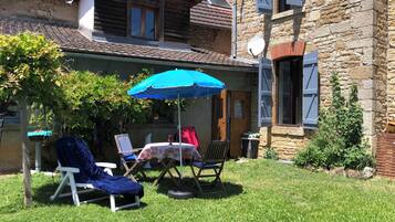 Een terras met tuinmeubilair, een tafel en een blauwe parasol.