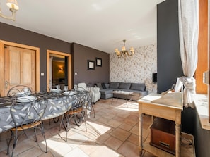 Un coin repas avec une table dressée pour quatre personnes, un canapé, un téléviseur et un lustre.